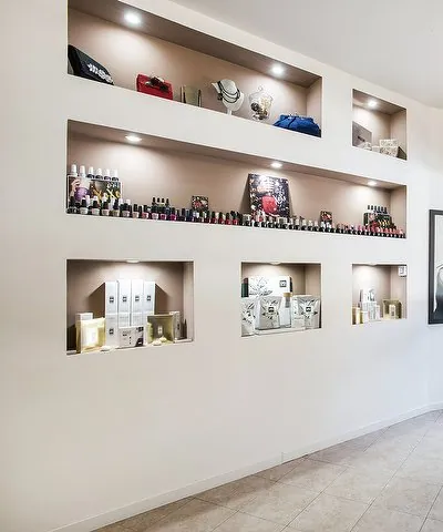 Le nicchie color cipria illuminate dai faretti, con gli smalti, le pochette e i prodotti per la cura del viso